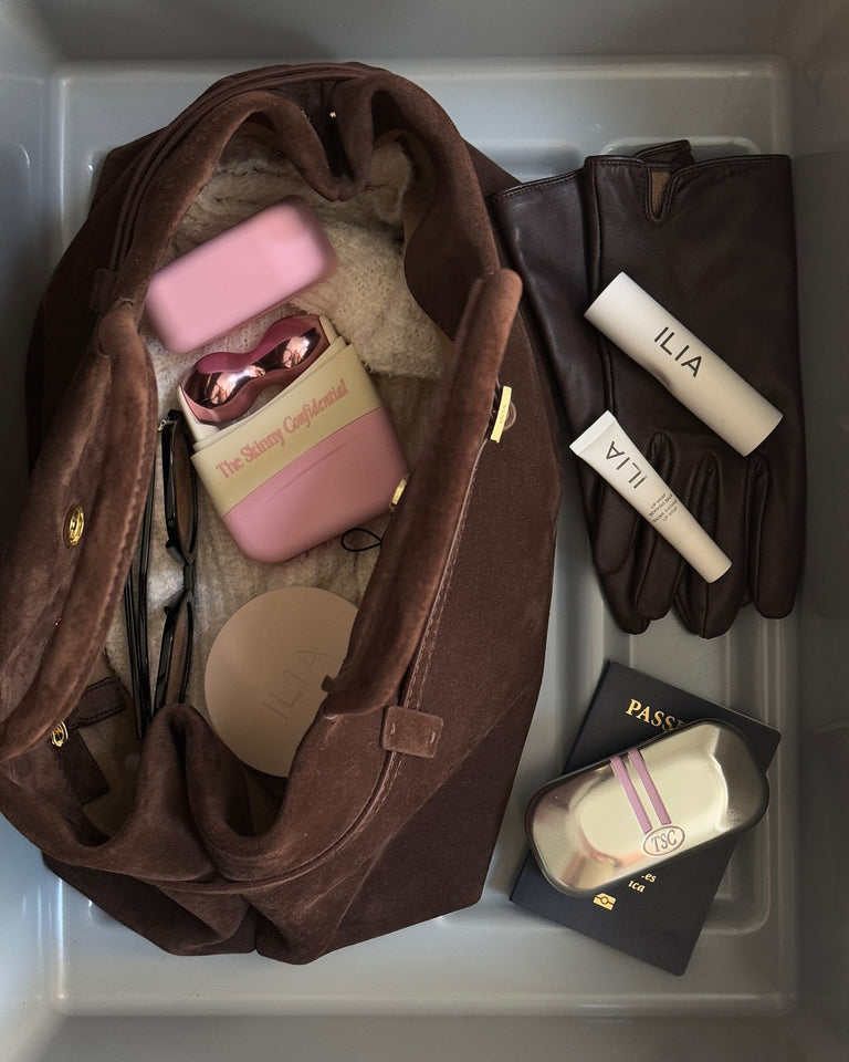 Brown handbag with beauty products, gloves, passport, and travel essentials. Brown handbag with beauty products, gloves, passport, and travel essentials.