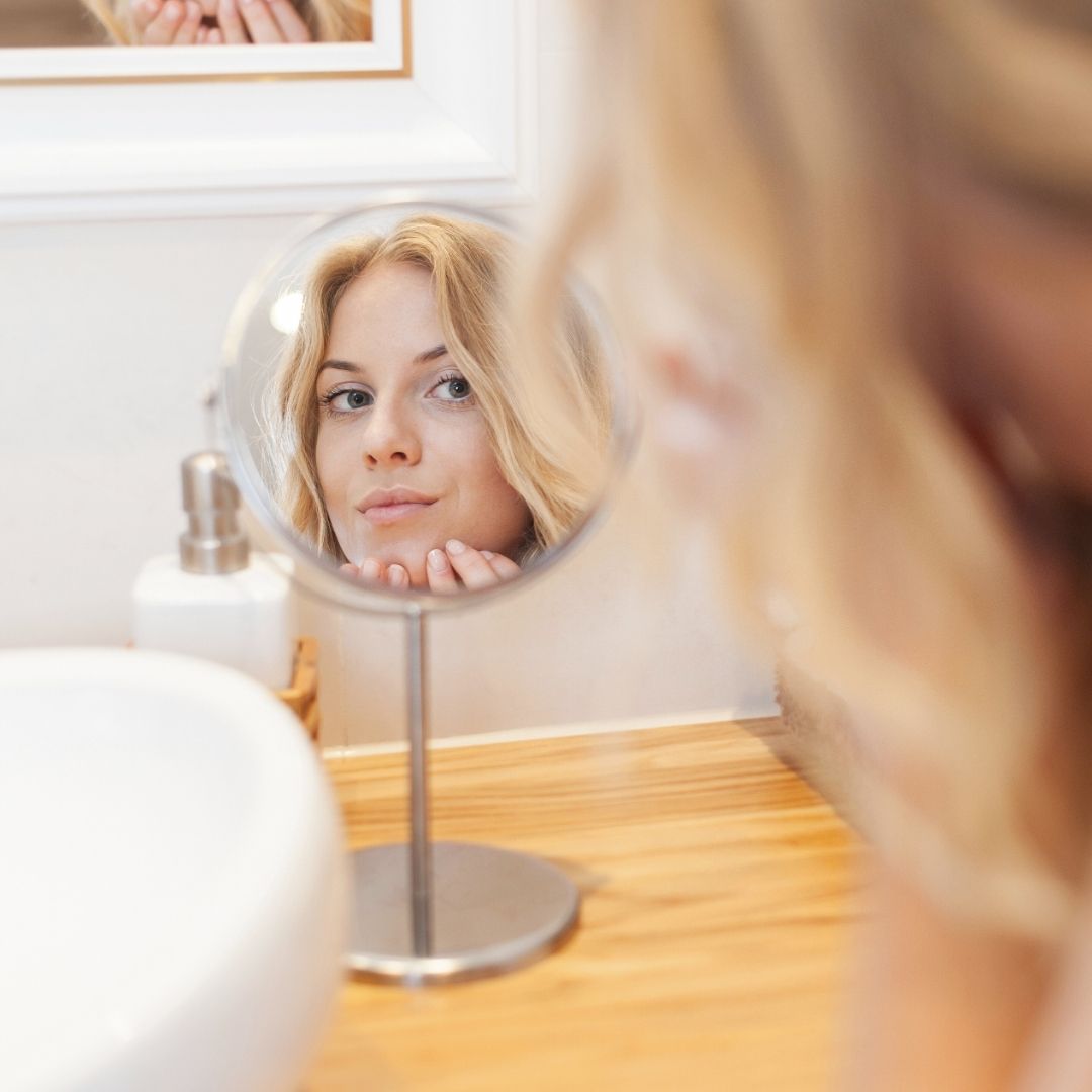 Girl looking at herself in round makeup mirror