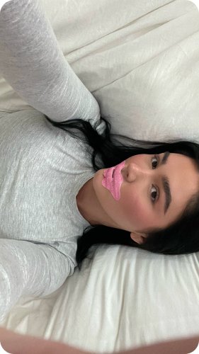 Selfie with pink lip mask on woman lying down.